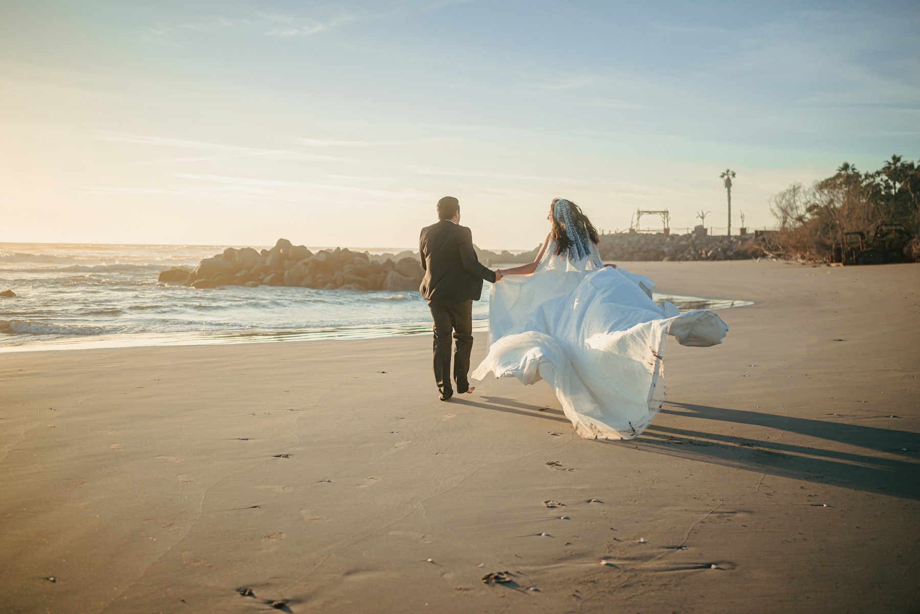 Newlyweds walking the beach at sunset